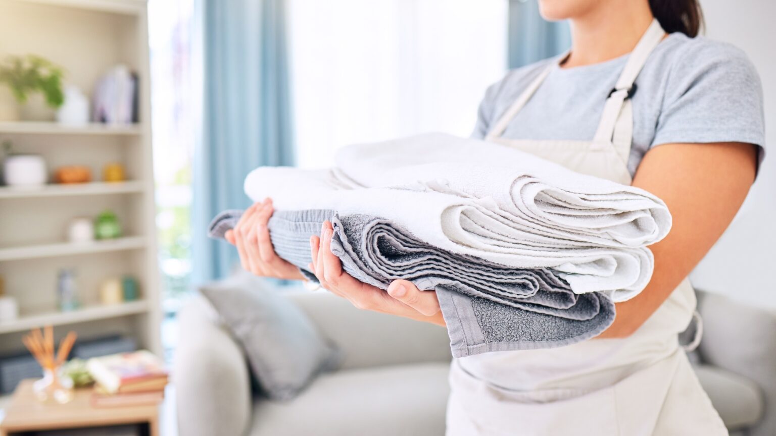Hands, clean towels and woman with laundry, linen or cotton textile in stack at home. Spring cleani