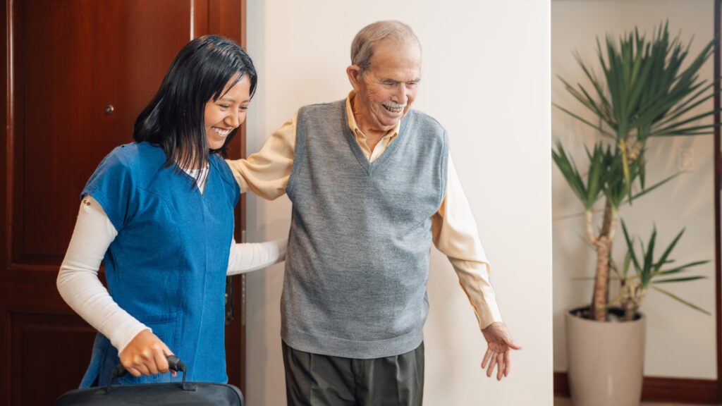 Nurse assisting an elder man visiting him at home